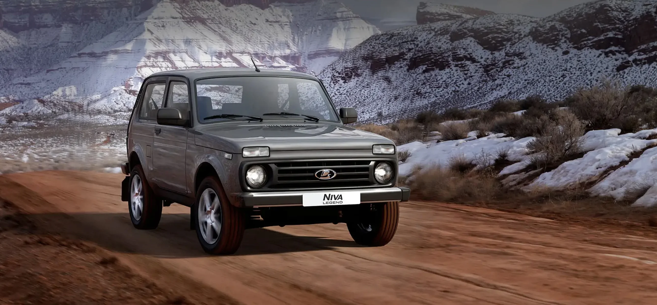 LADA Niva Legend 3-дв серый вид 3/4 спереди на&nbsp;грунтовой дороге среди каменистых гор
